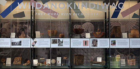 A display case with images, text panels, and a range of baskets inside.


